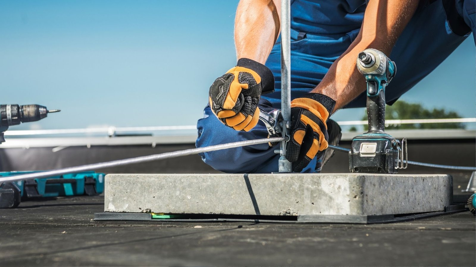 Technician securing a concrete ballast block installation on a rooftop.