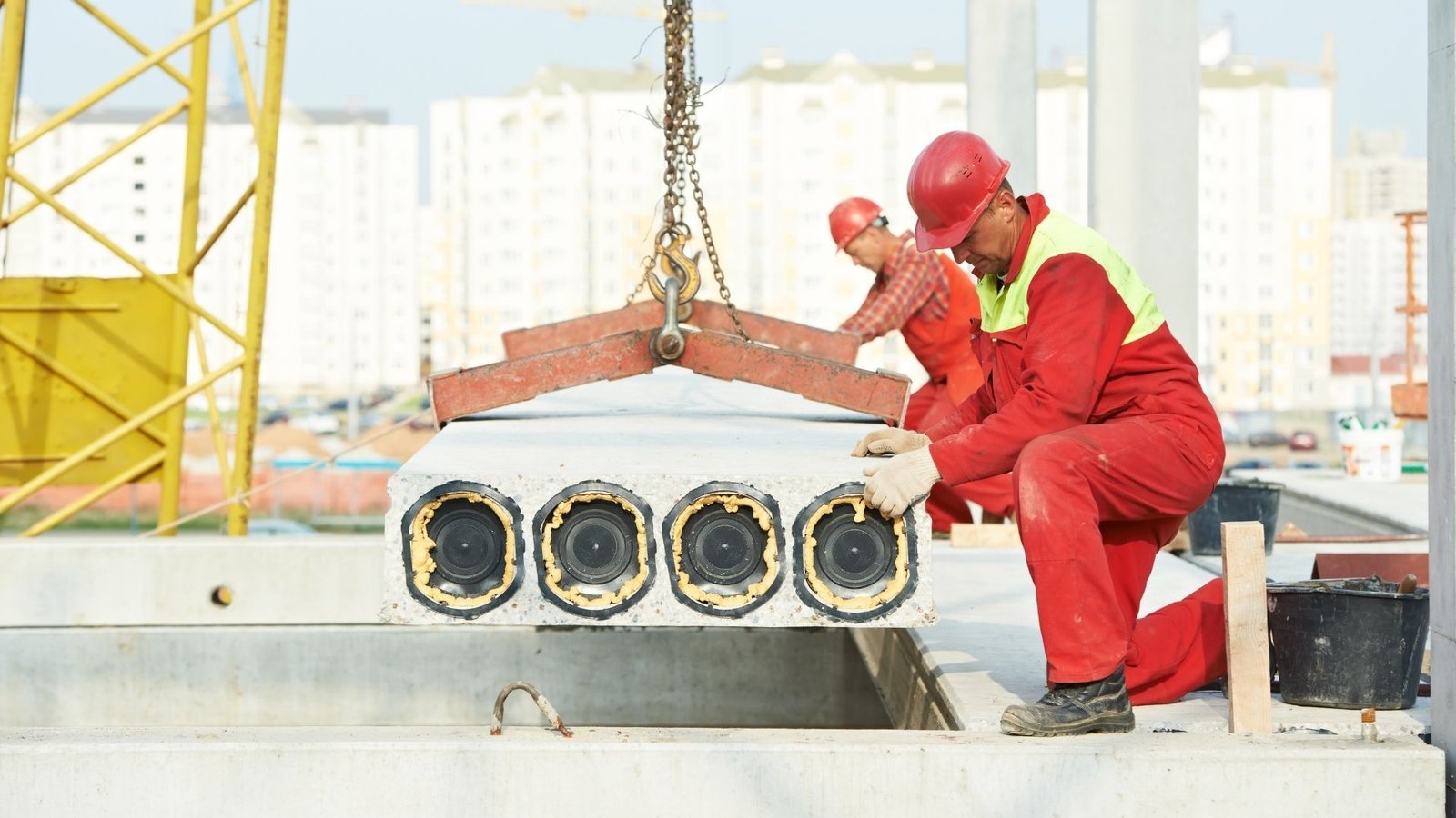 Construction workers installing a precast concrete structural element.