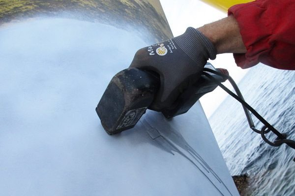 Close-up of a technician using a measurement device to assess coating condition on offshore steelwork.