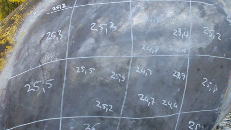 Coating thickness measurement grid marked on a steel surface.