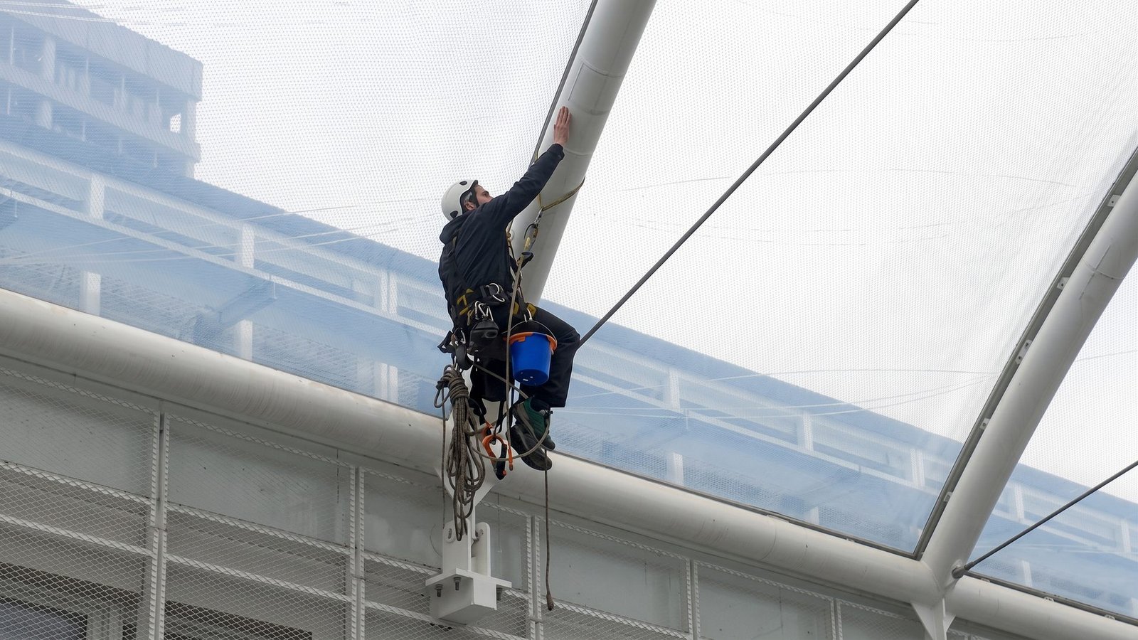 Rope access technician working on an industrial roof structure.
