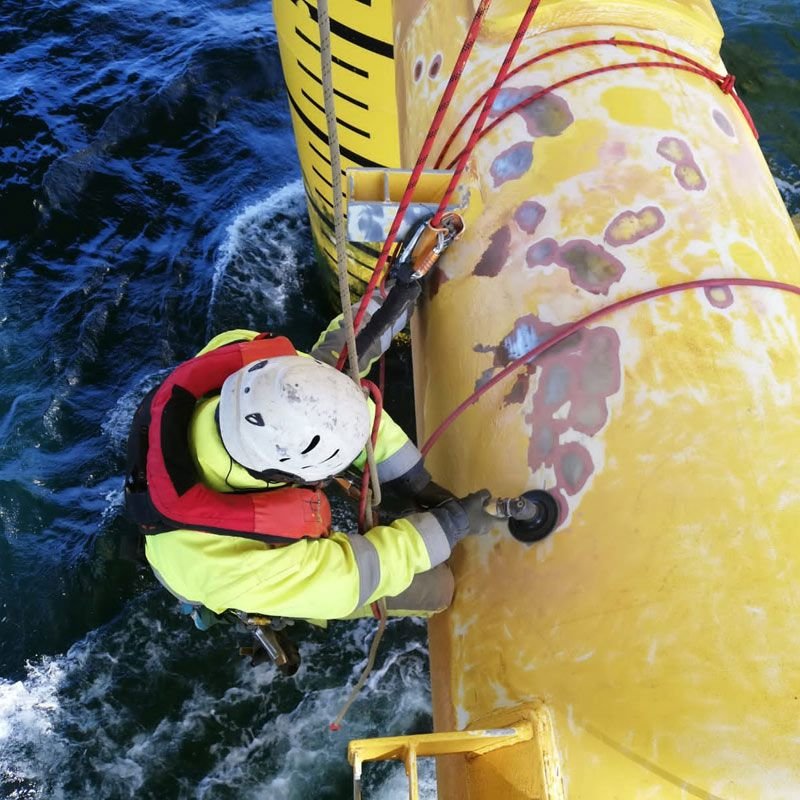 Rope access technician inspecting an offshore structure above the sea.