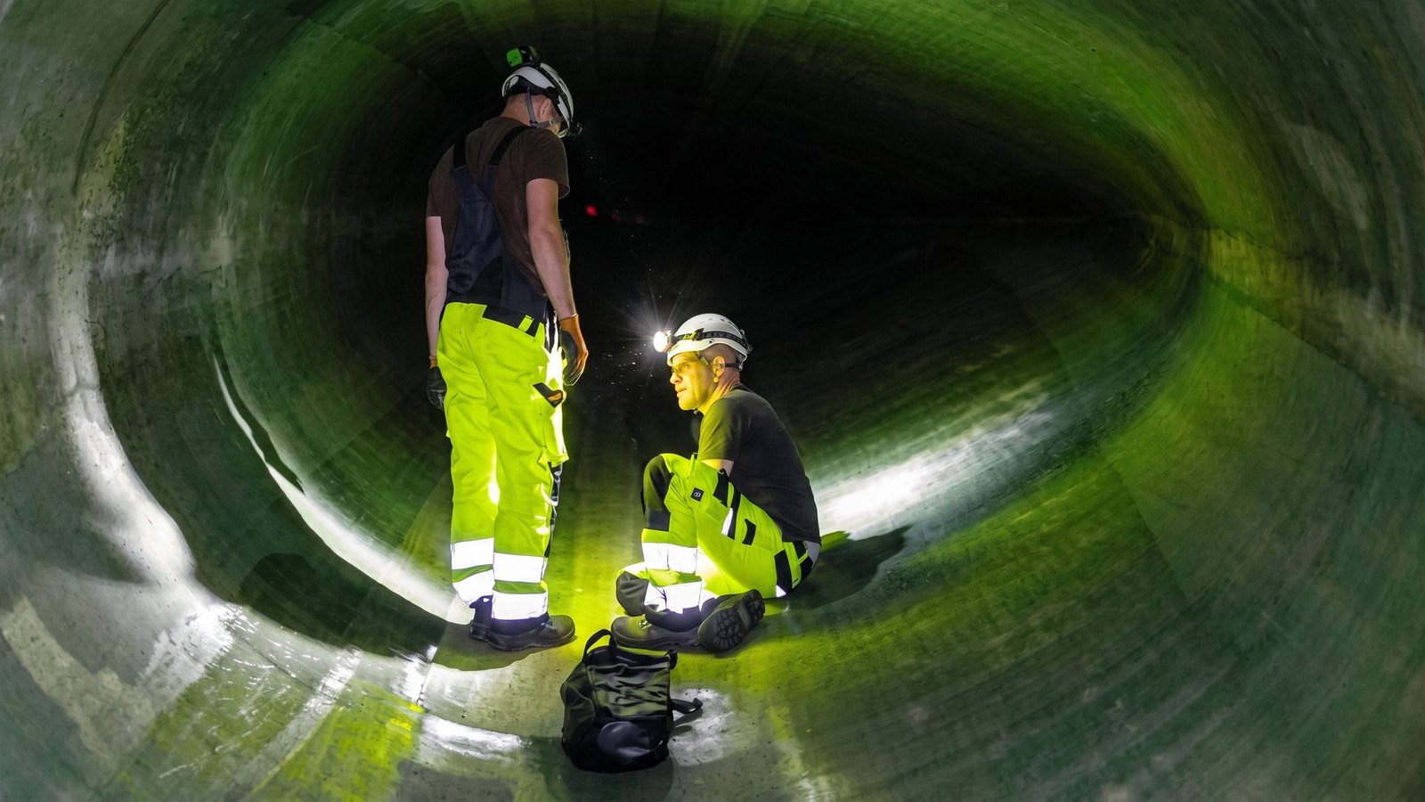 Two technicians inspecting the interior of a wind turbine rotor blade.